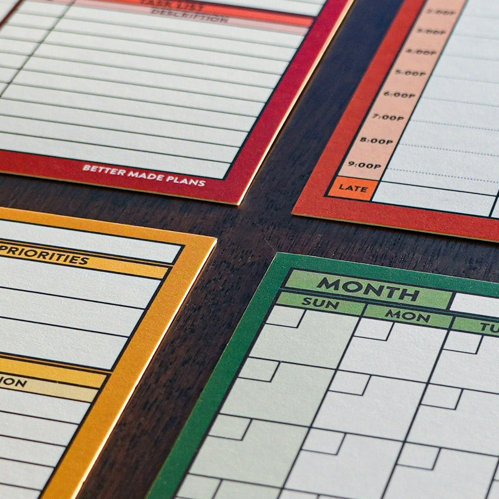 Closeup of colorful Better Made Plans planning cards laying on a wooden tabletop.