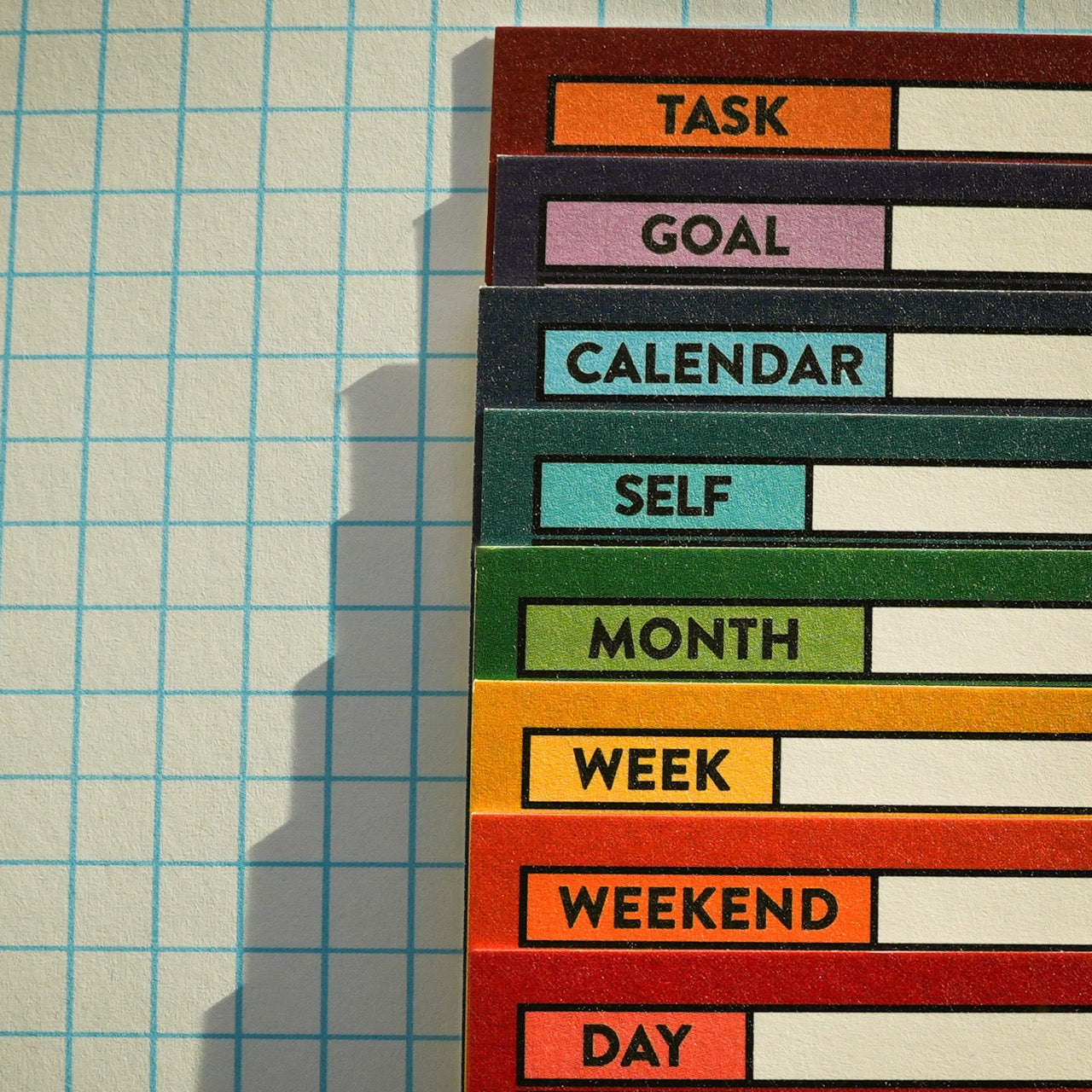 Close up of upper left corner labels on stack of Better Made Plans planning cards on a graph paper background.