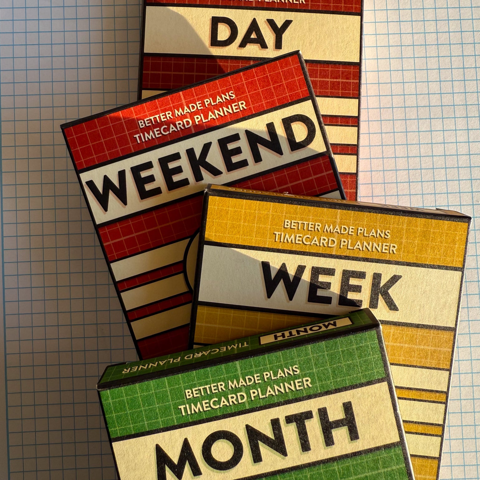 Packaging for Better Made Plans Day, Weekend, Week, and Month planning cards laying stacked on a graph paper background.