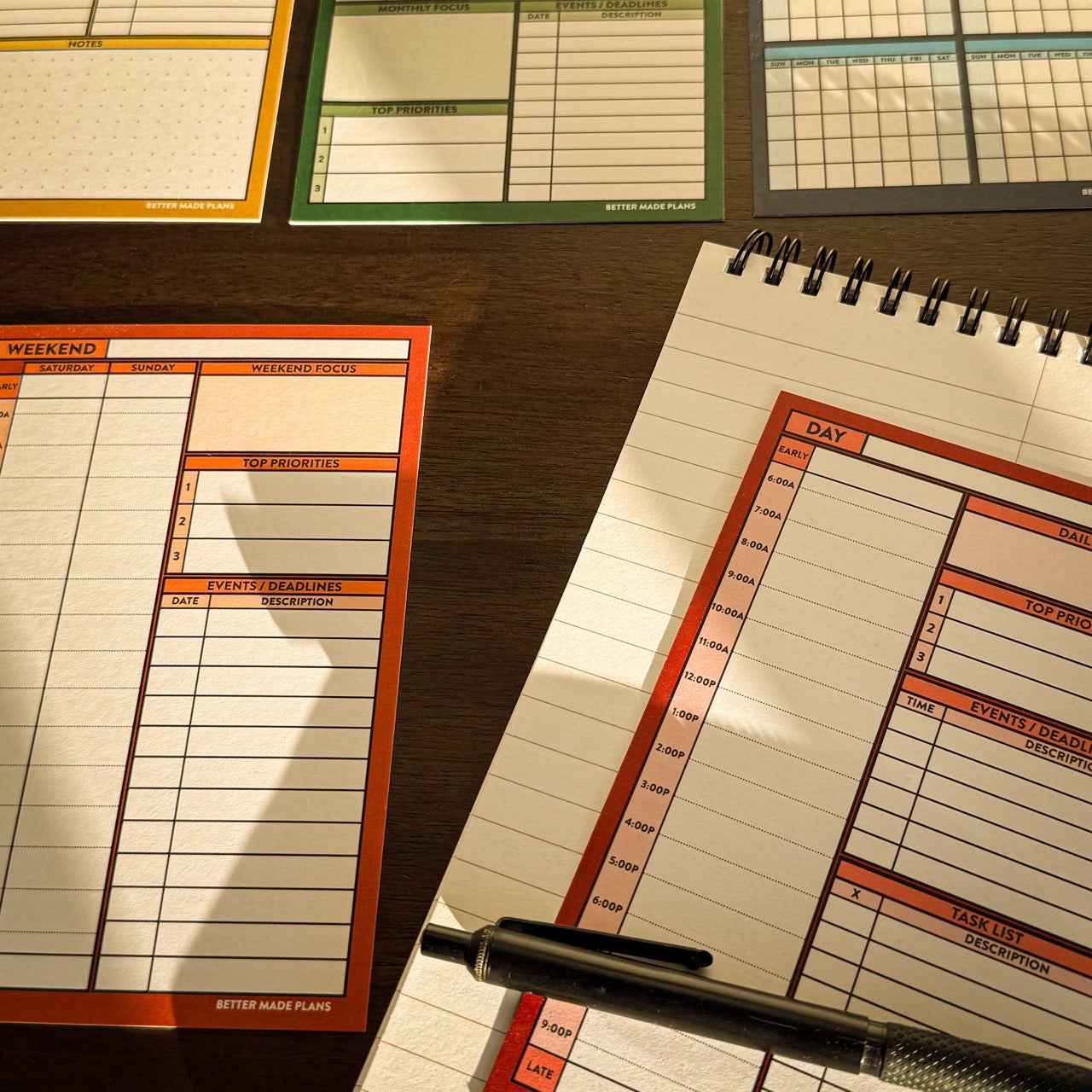 Various Better Made Plans planning cards on a table top with a notebook and pencil.