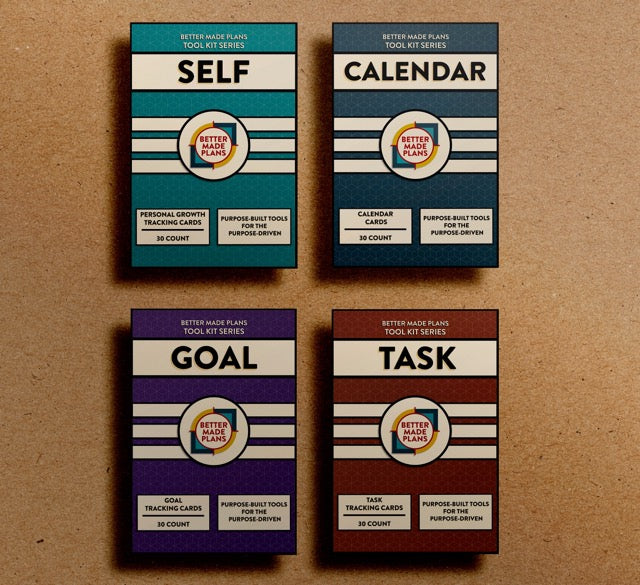Packaging for the Better Made Plans Tool Kit Series of Planners including Self, Calendar, Goal, and Task editions laying on a brown paper background.